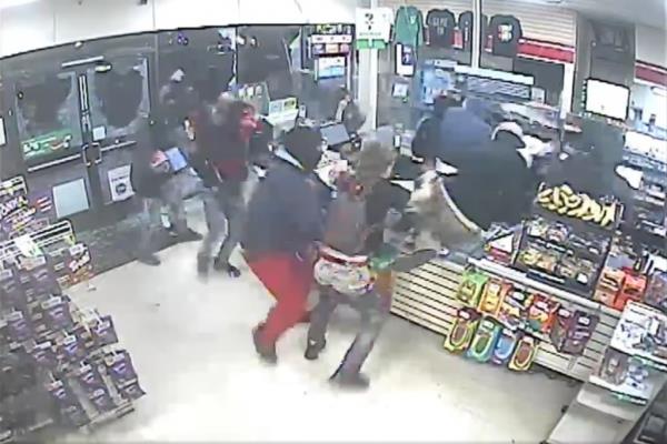 Grainy surveillance footage showing a large group of people jumping over a counter at a 7-Eleven co<em></em>nvenience store as they steal merchandise.